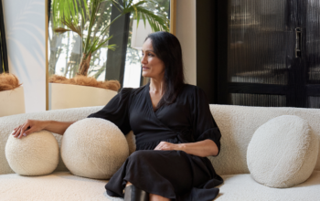 A women sitting on a couch and staring off to the side. She looks like she is in a home setting.
